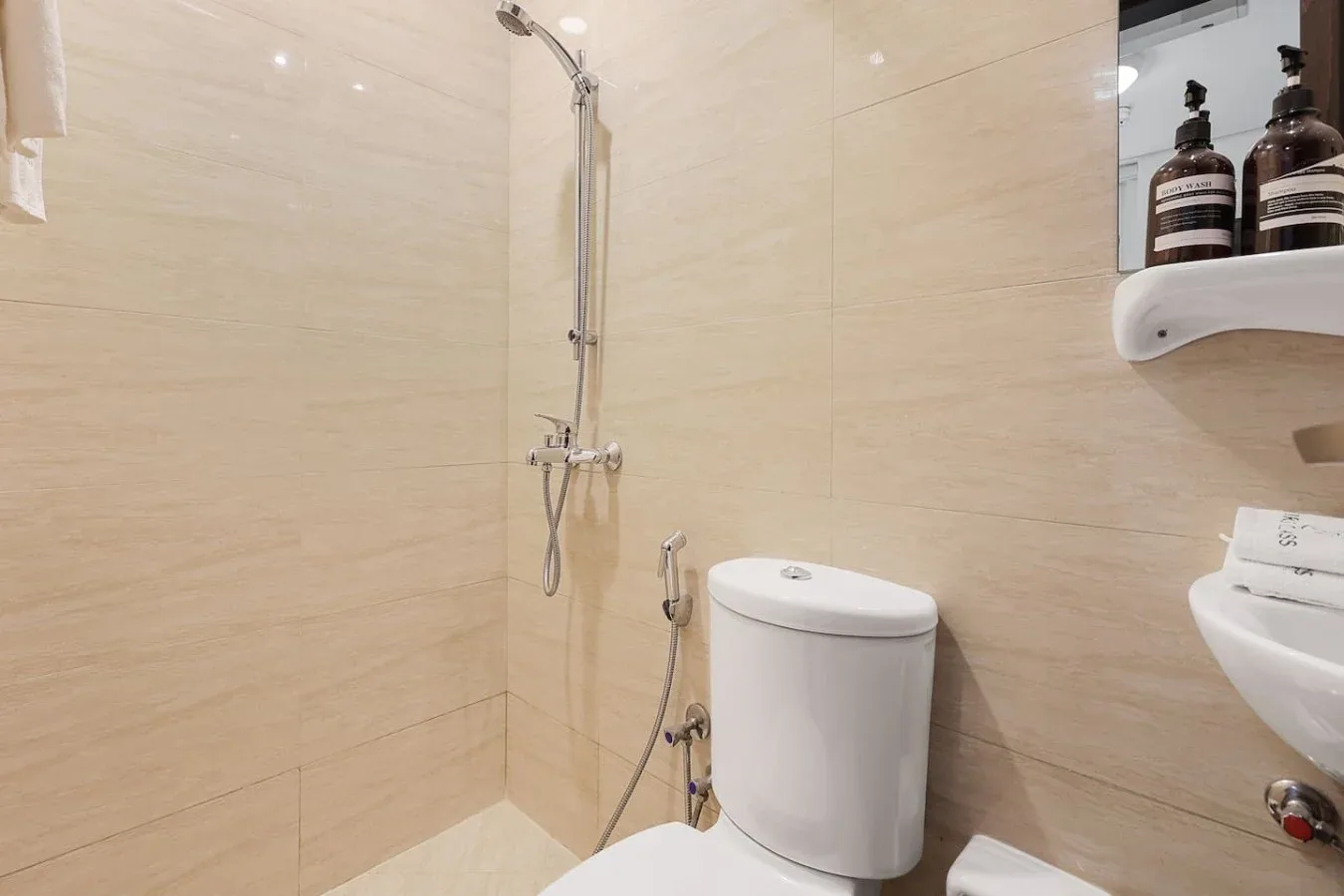 Un baño con ducha, inodoro y lavabo, con paredes revestidas de azulejos.