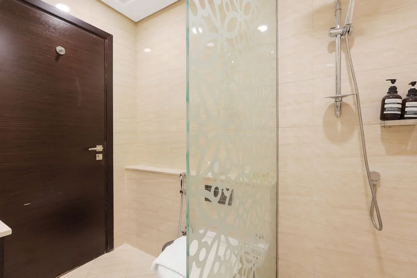 Un baño revestido de azulejos con ducha y mampara de vidrio decorada.