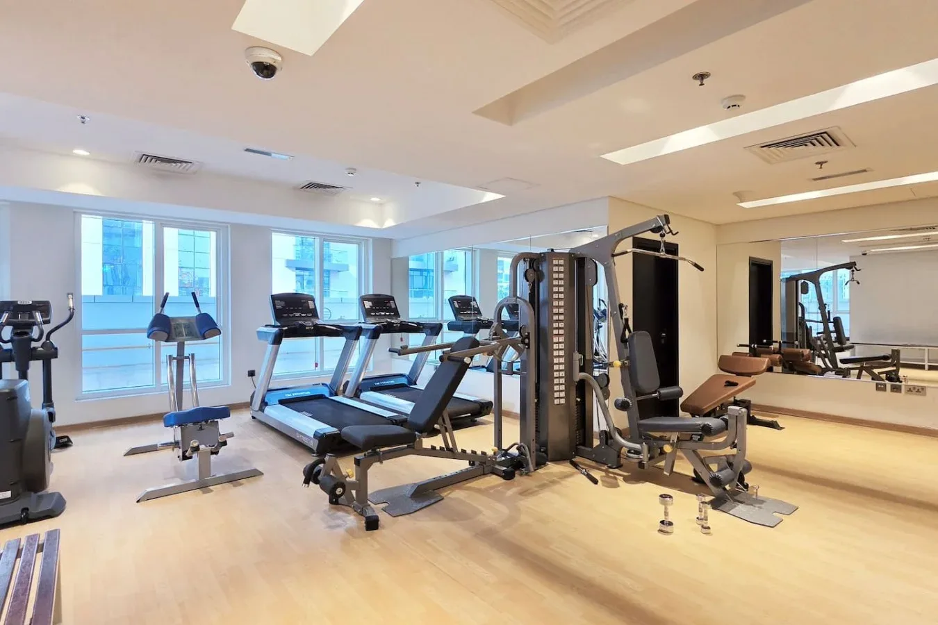 Un gimnasio con cintas de correr, máquinas de pesas y ventanales.