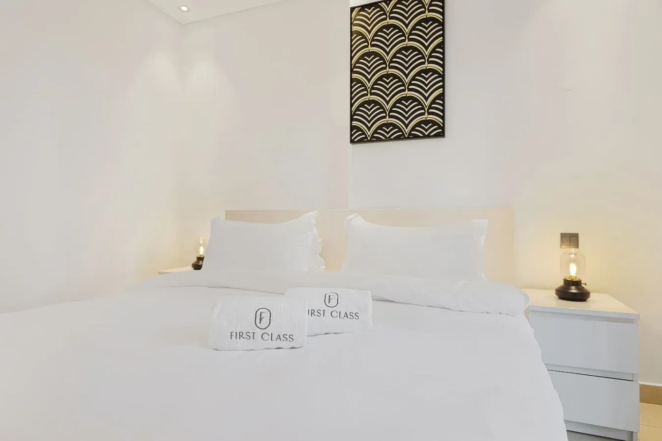 Un dormitorio con una cama bien tendida, mesas de noche y arte mural estampado.