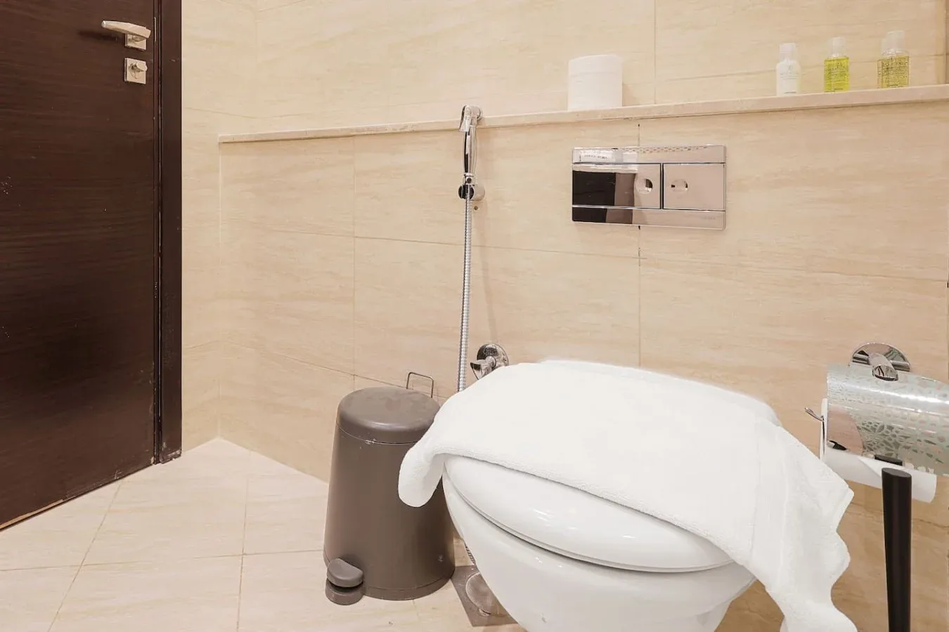 Un baño con un inodoro, una toalla y una ducha de mano.