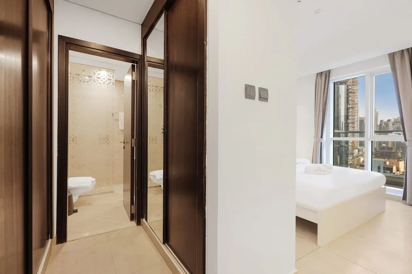 Un dormitorio luminoso con una cama blanca junto a ventanas de piso a techo.