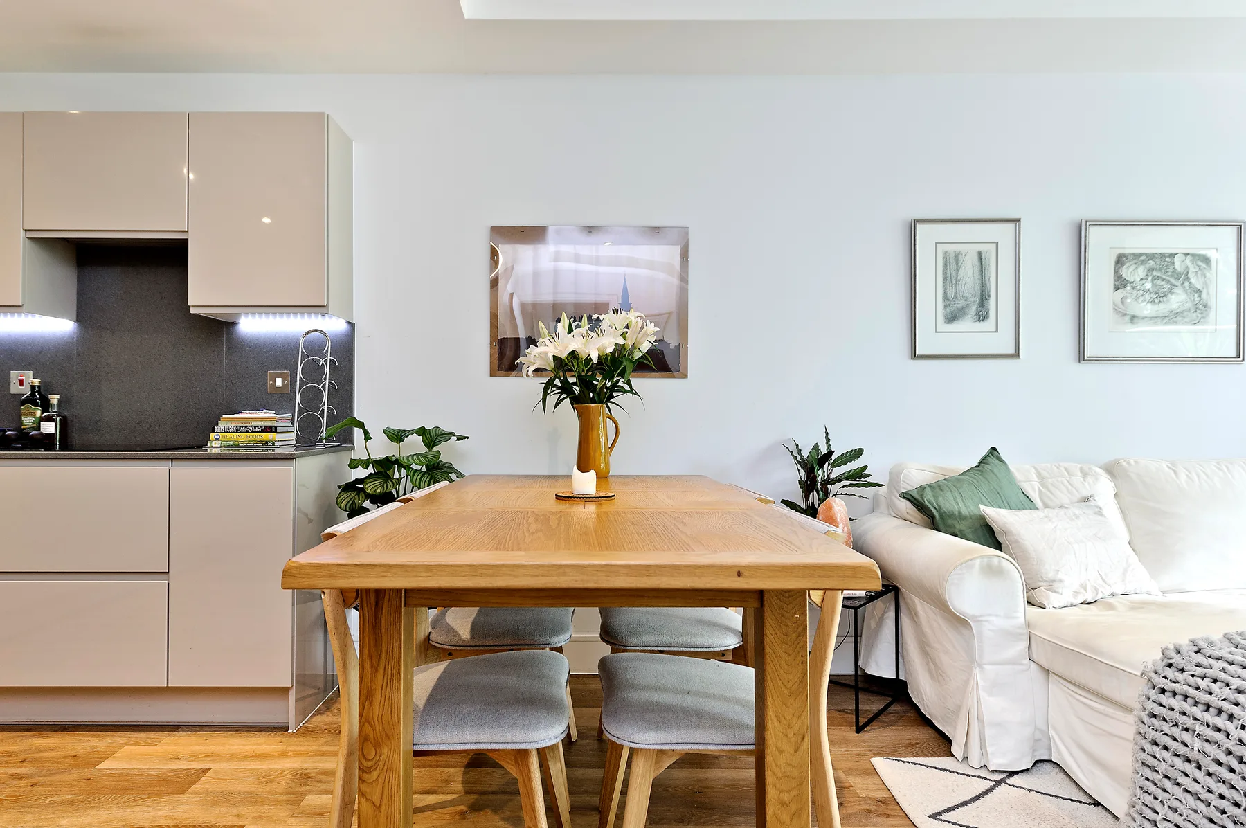 A dining area with a wooden table beside a compact kitchen and seating.