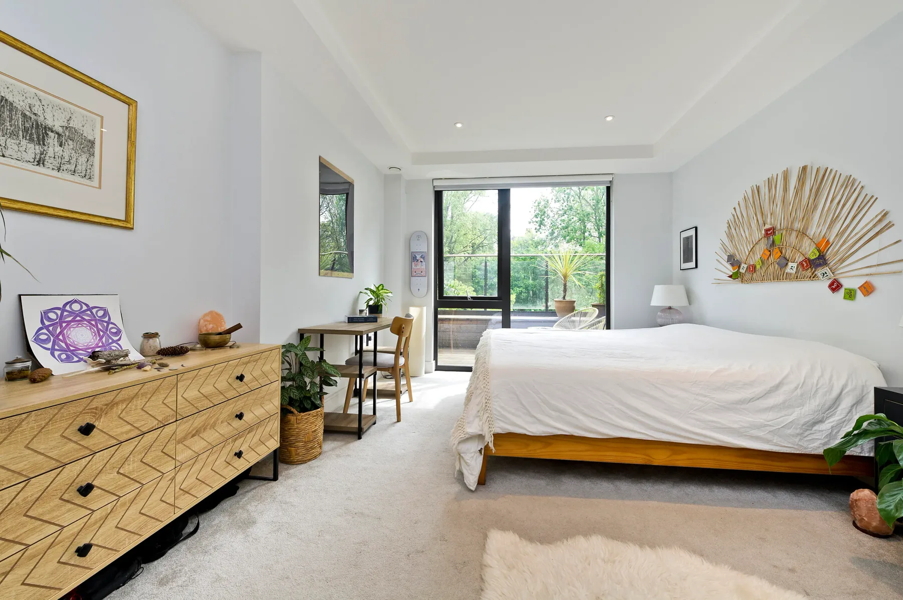 Un dormitorio luminoso con una cama grande y ventanas con vistas a la vegetación.