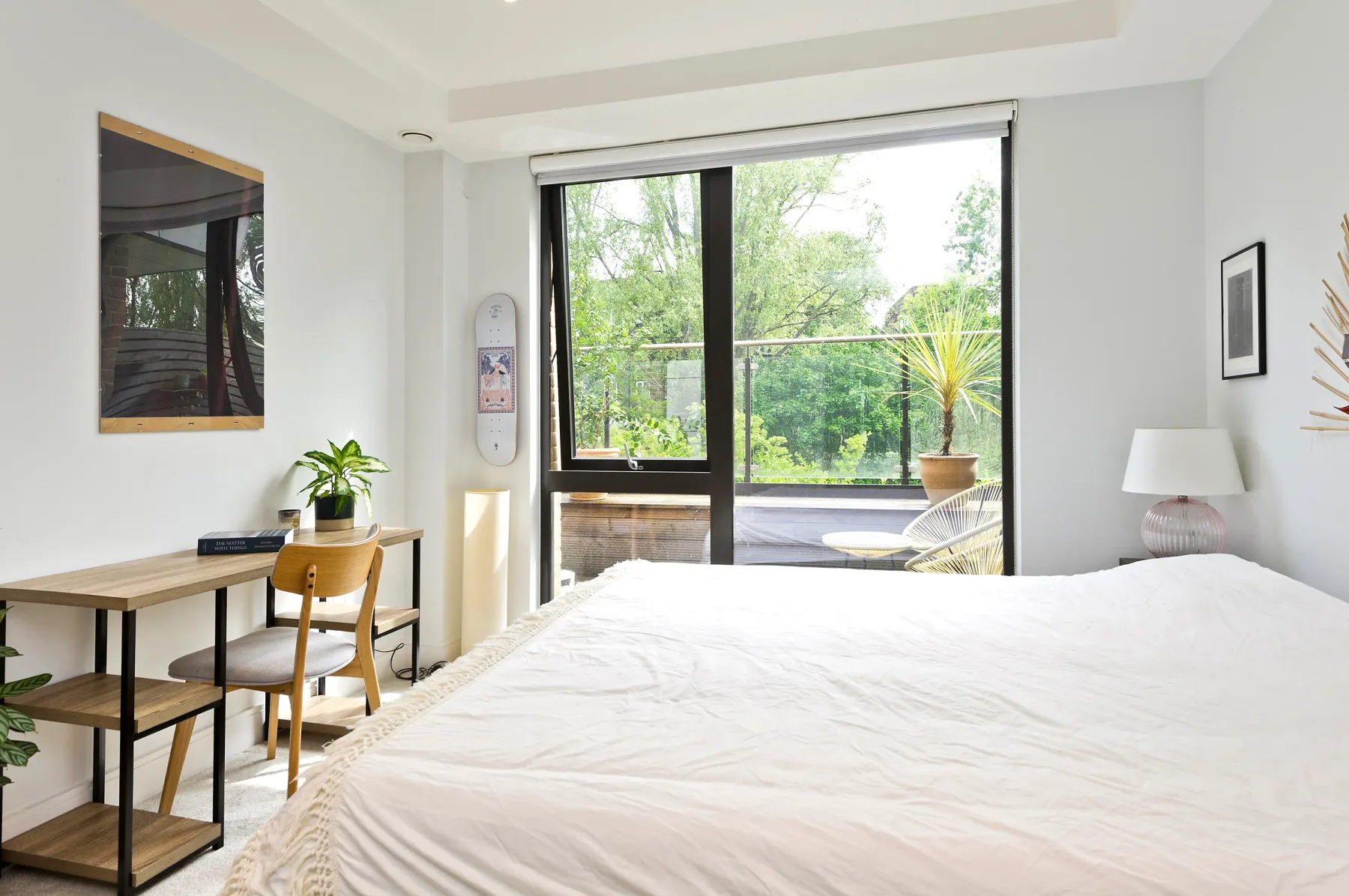 Un dormitorio luminoso con una cama grande junto a una ventana con vistas a la vegetación.