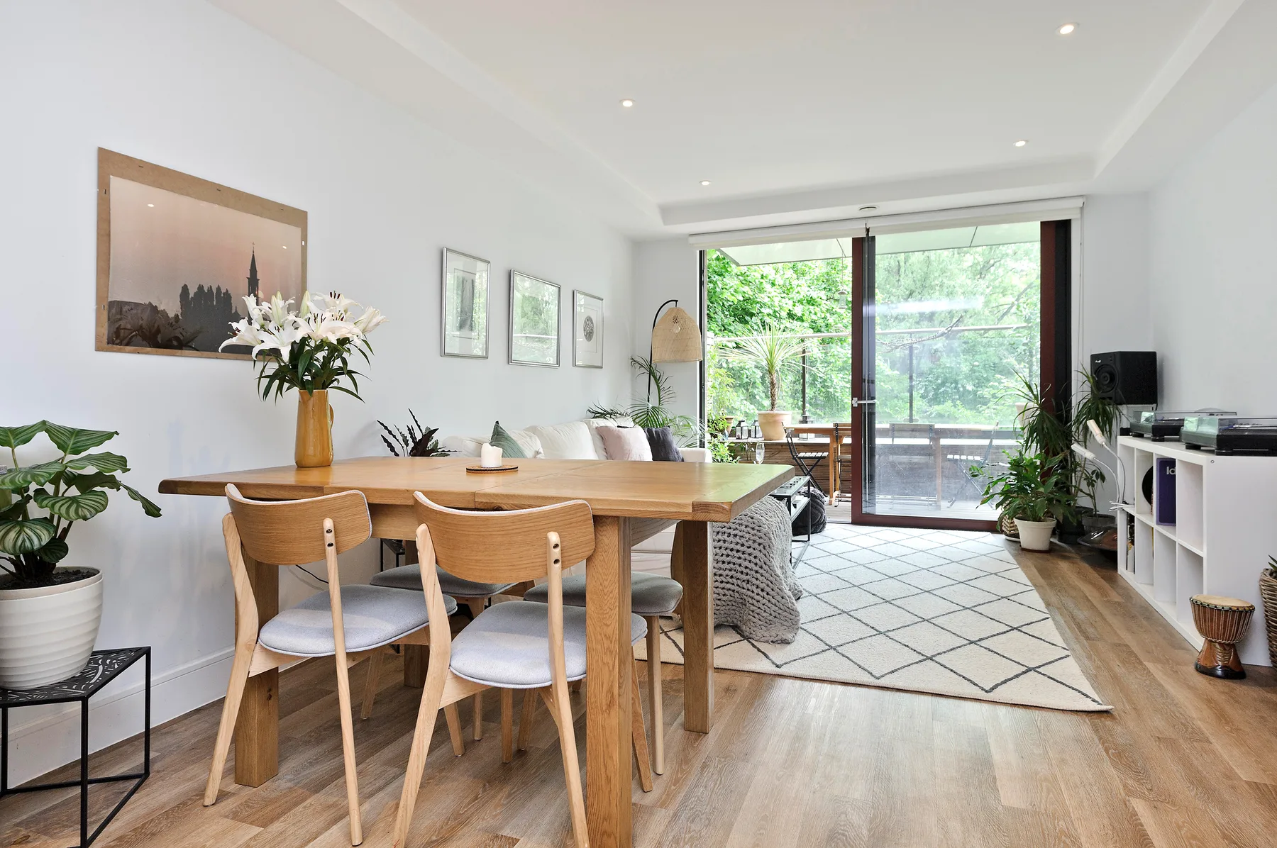 Comedor con asientos de madera y una puerta de vidrio abierta hacia la vegetación.