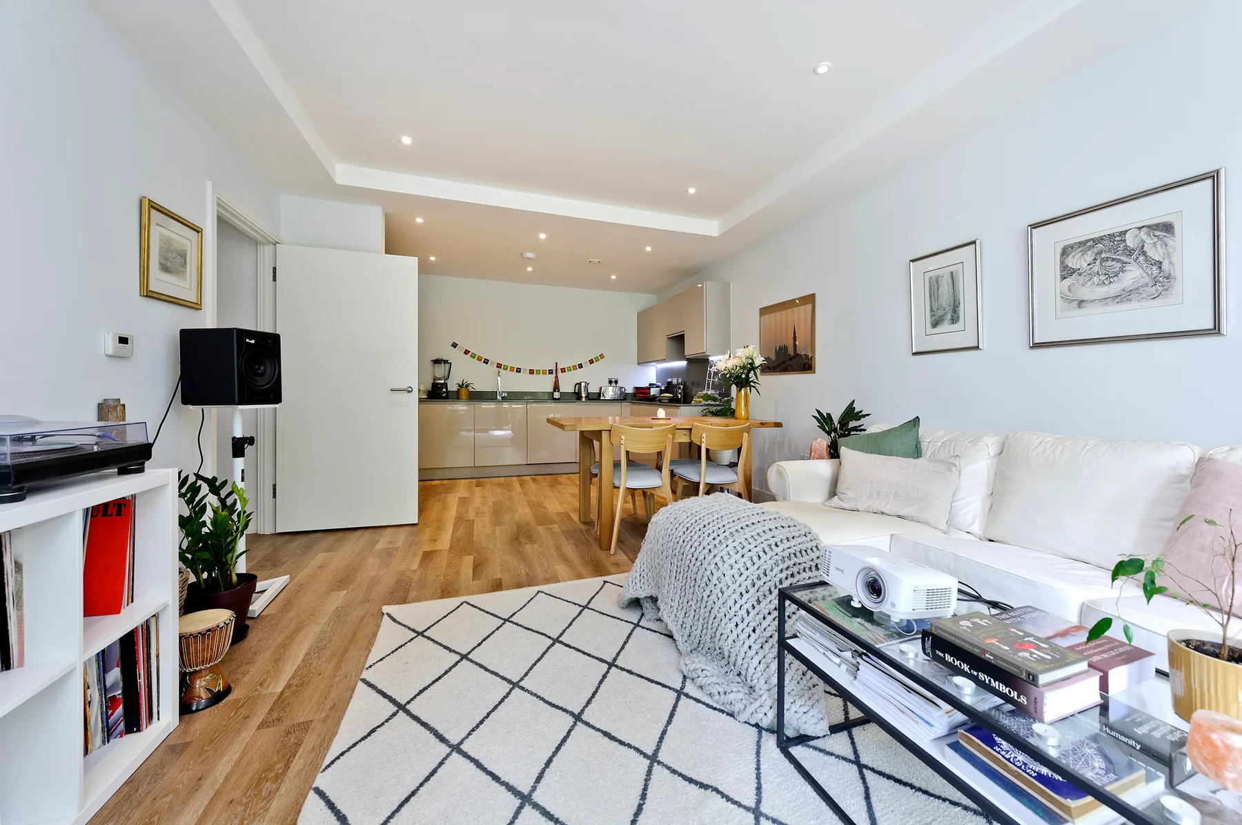 A bright living and dining area with a white sofa and wooden table.