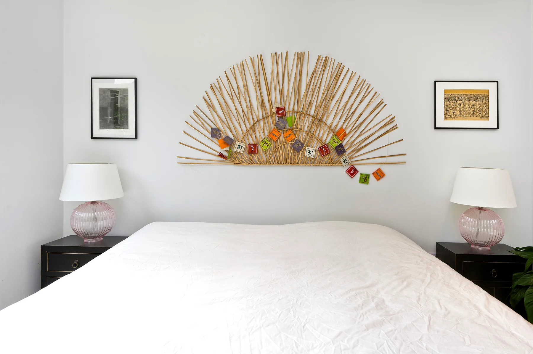 Un dormitorio con una cama blanca bajo un adorno de pared.