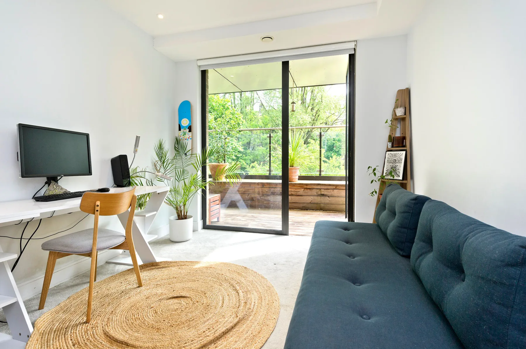 Una sala luminosa con escritorio, asientos y puertas corredizas de vidrio que dan a la vegetación.