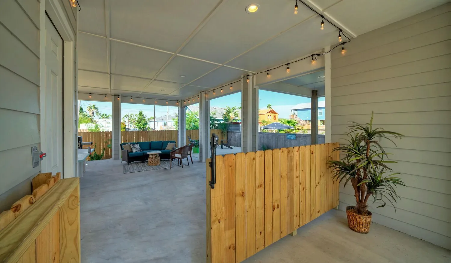 A covered patio with seating, string lights, and a wooden half-wall.