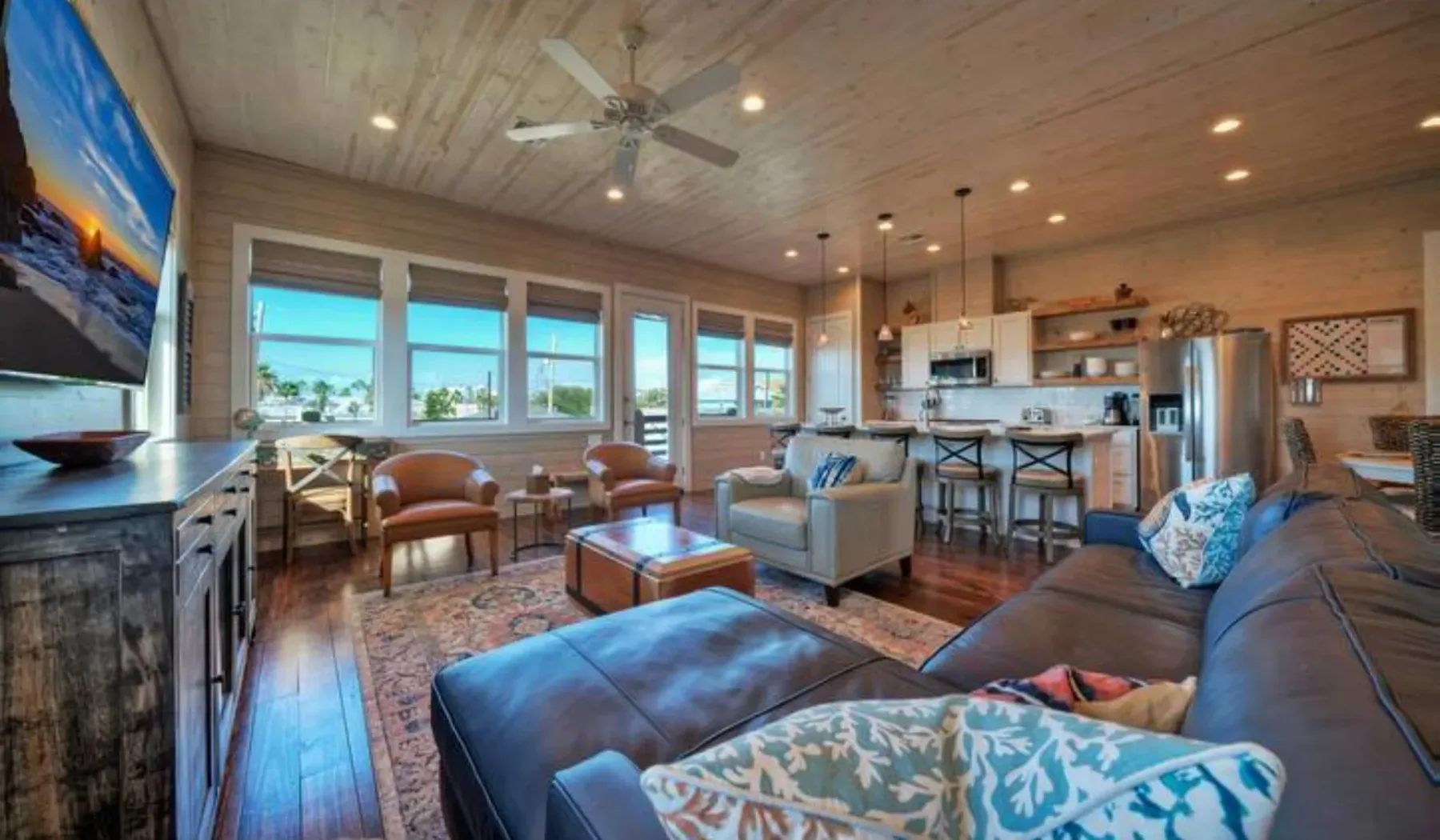 A spacious living room with seating, large windows, and an open kitchen.