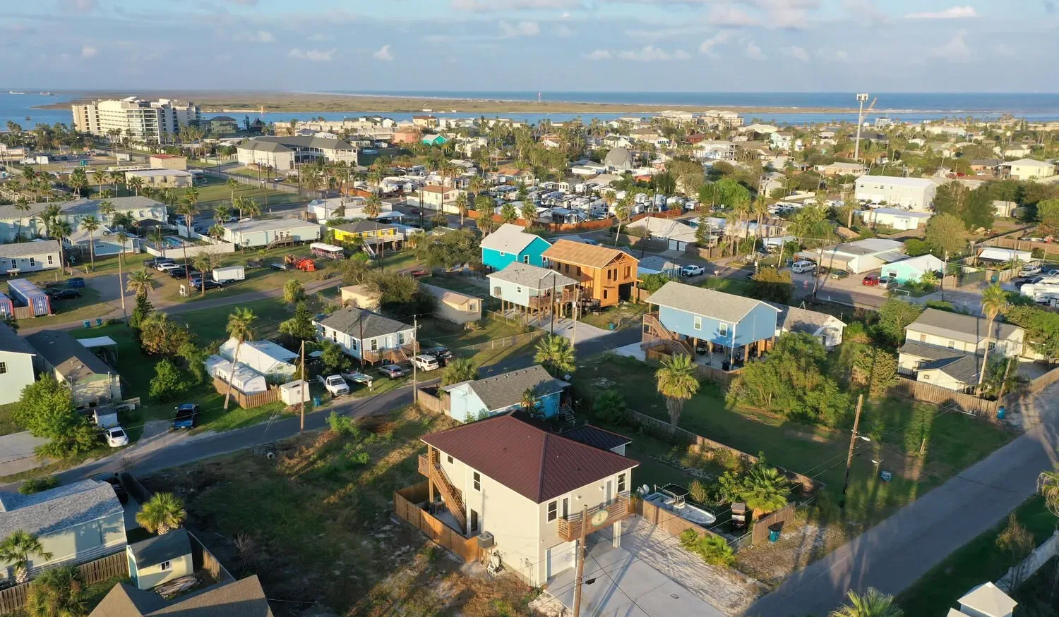 Aerial view of a coastal town with buildings, roads, and the sea beyond.
