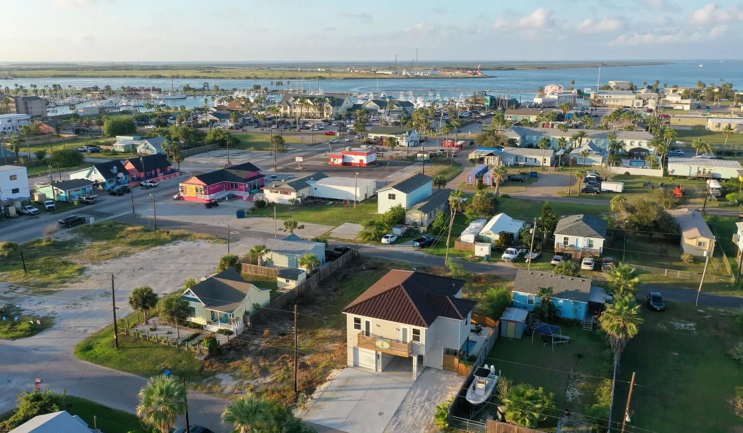 Aerial view of a coastal neighborhood with houses and water in the distance.