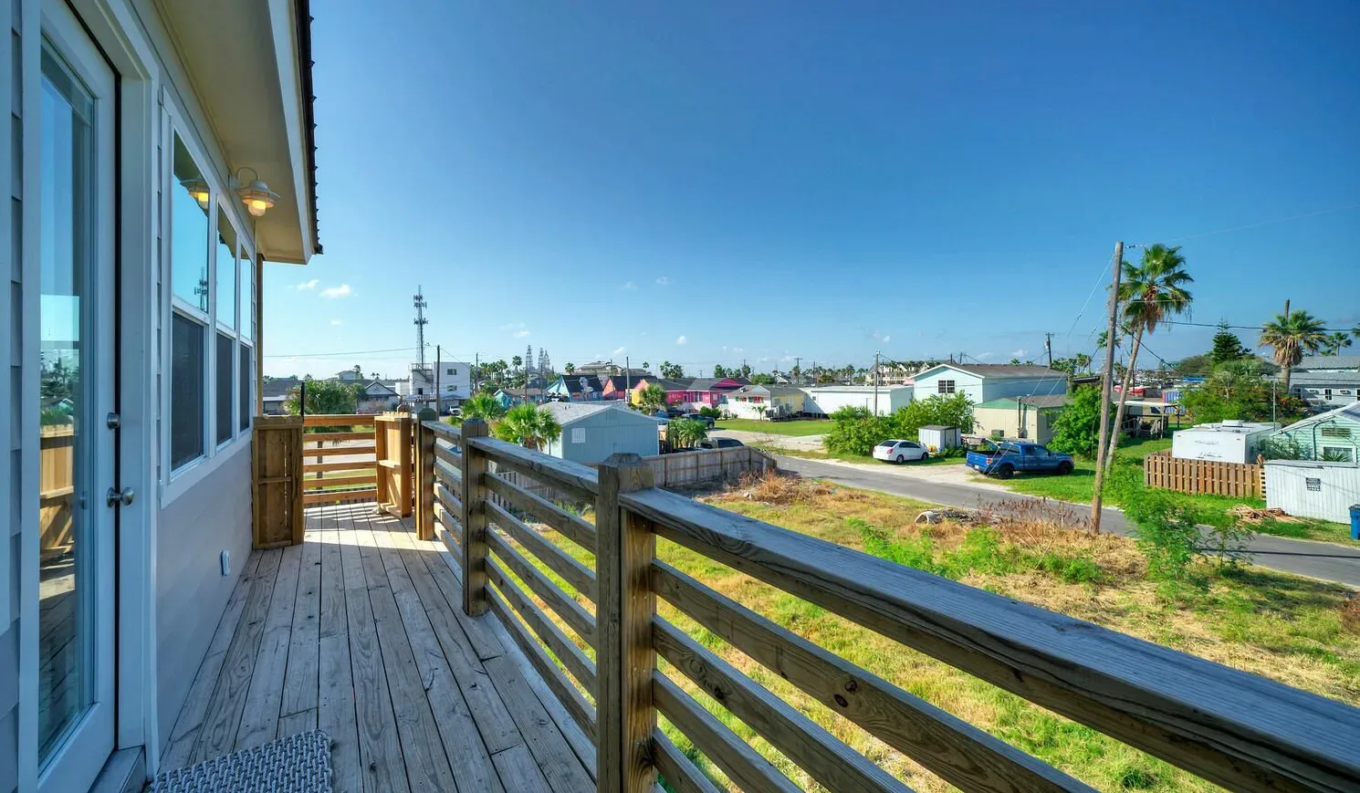 A wooden deck overlooks a residential neighborhood under a clear blue sky.