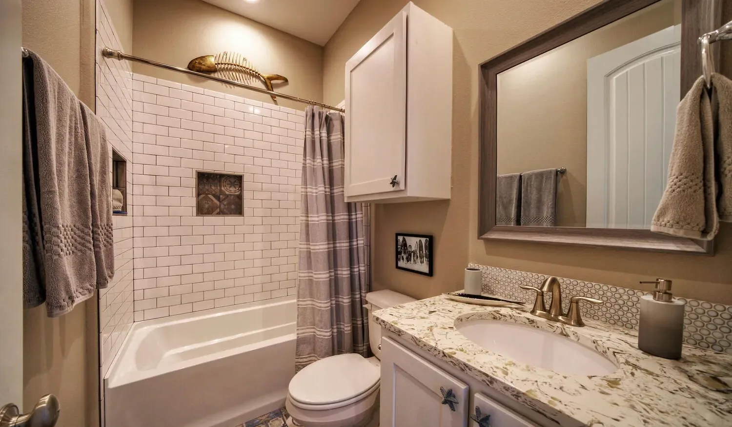 A bathroom with a bathtub, shower curtain, toilet, and sink.