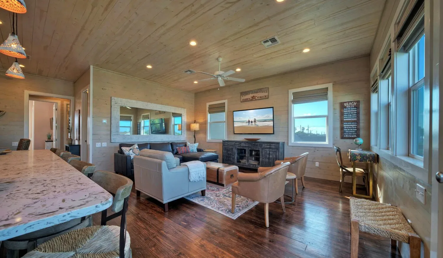 A spacious living room with seating arranged around a fireplace and wall-mounted television.