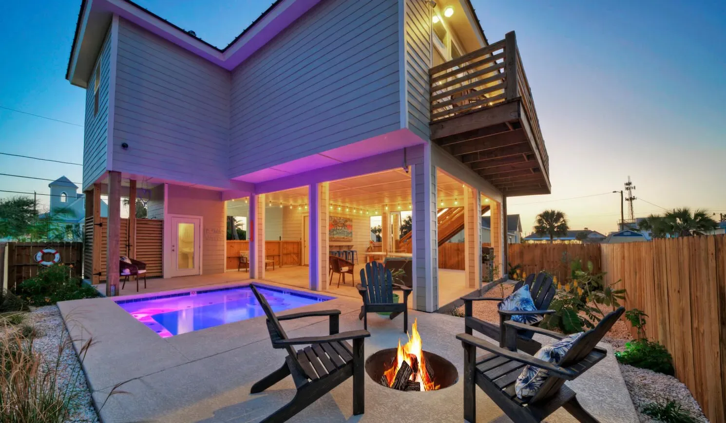 Un patio exterior con piscina, asientos y fogón junto a una casa.