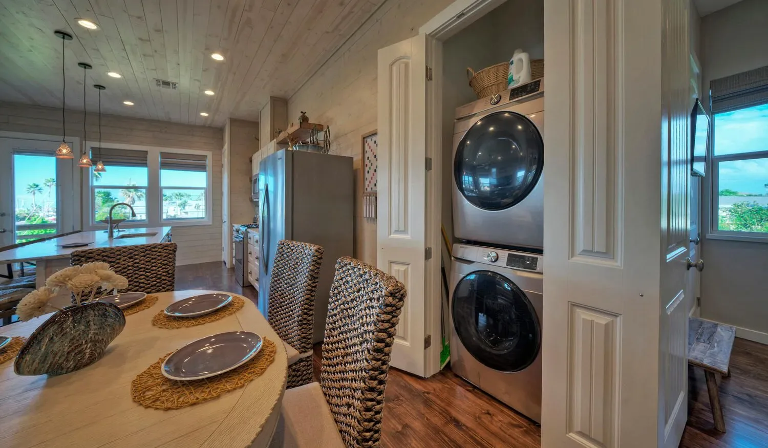 A dining area with woven seating beside a stacked washer and dryer.