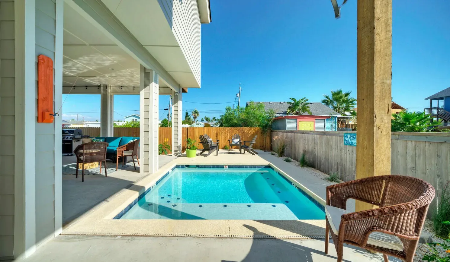An outdoor pool beside a covered patio with seating.
