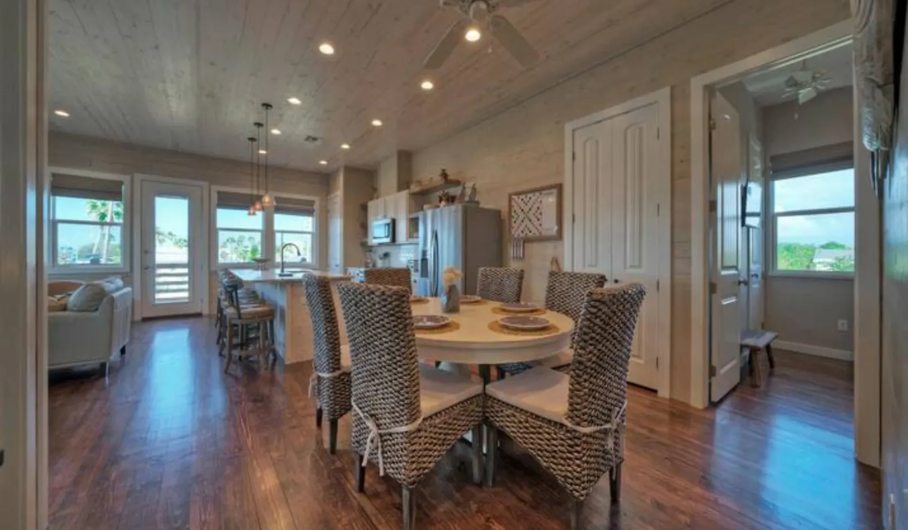 An open dining area with a round table and woven seating beside a kitchen.
