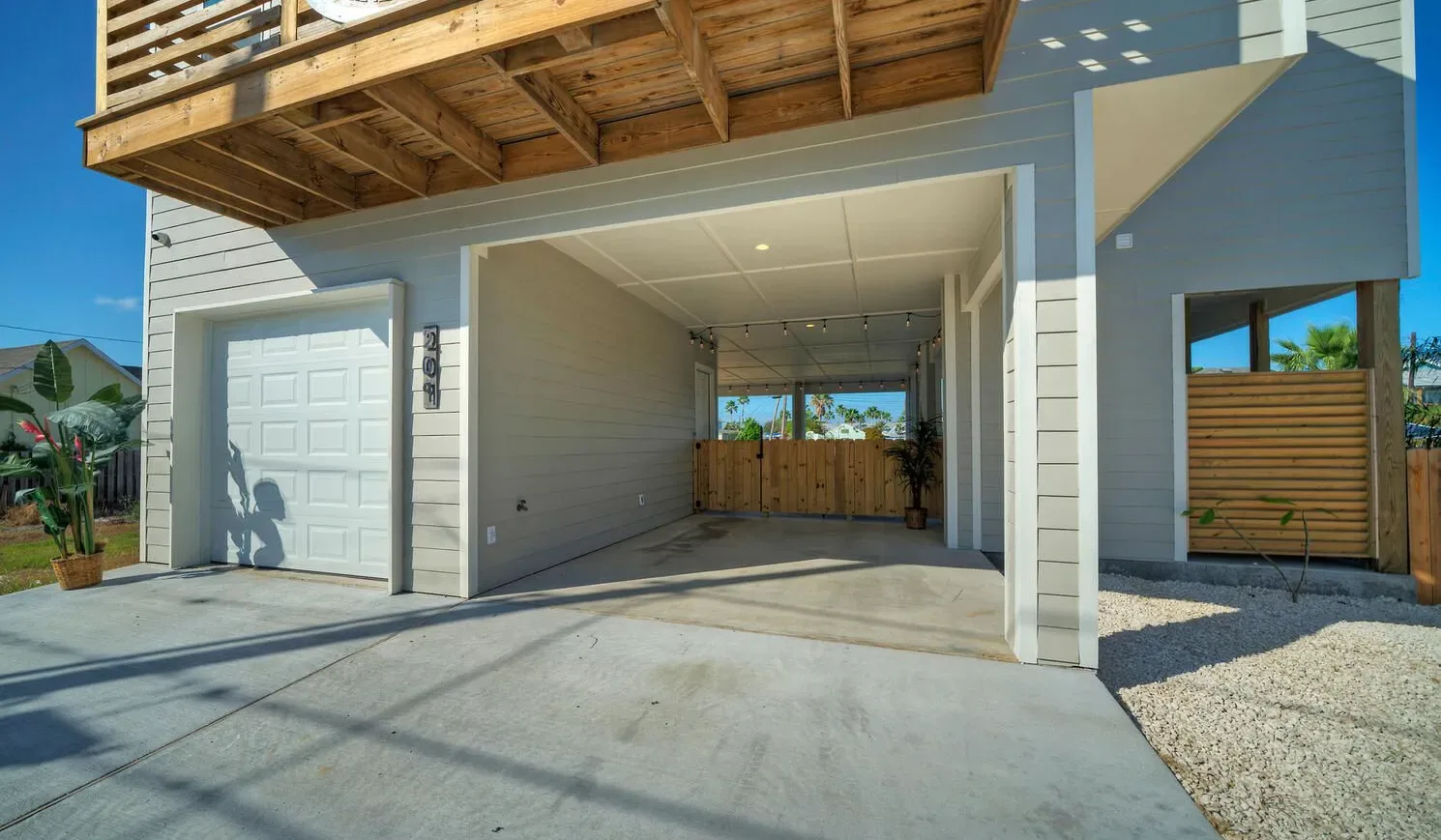 A house exterior with an open garage and a wooden balcony above.
