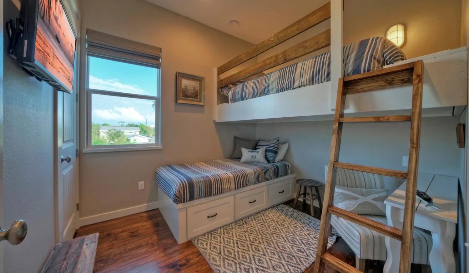 A compact bedroom with bunk beds, striped bedding, and a patterned rug.