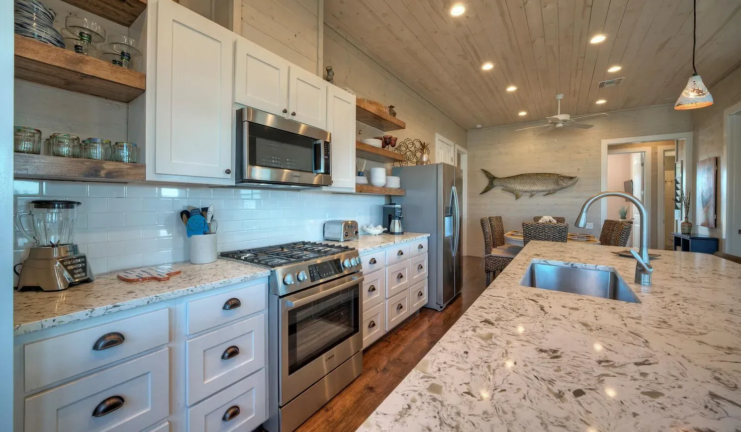 A bright kitchen with white cabinets, a range, and a large island.