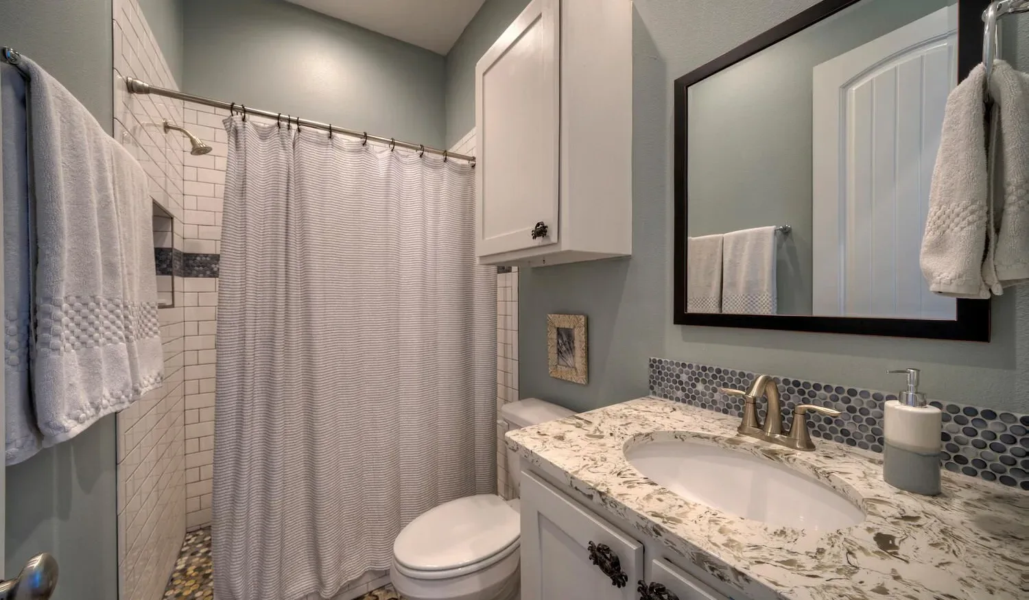 A bathroom with a curtained shower and a sink vanity.