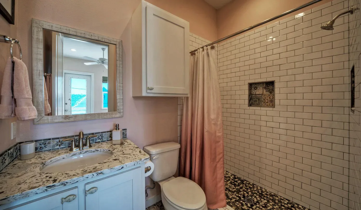 A bathroom with a sink vanity, toilet, and tiled shower.