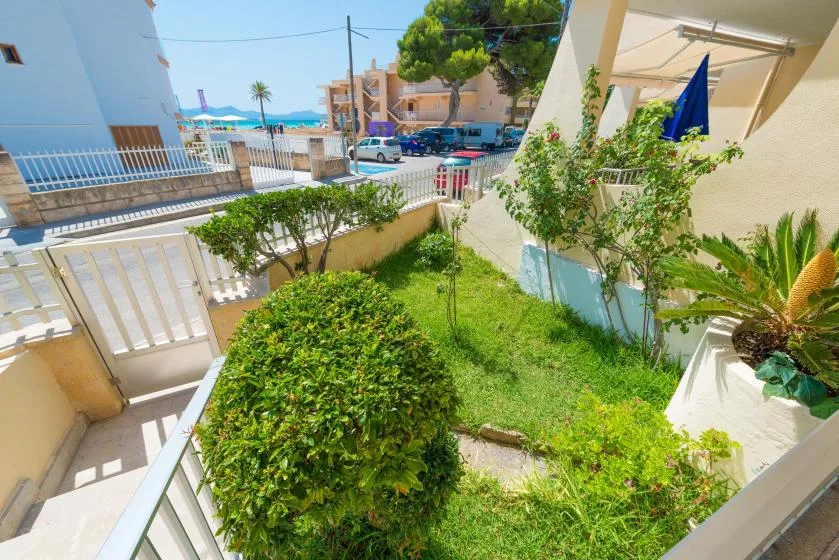 Un pequeño jardín ajardinado está junto a un sendero, con la calle y el mar al fondo.