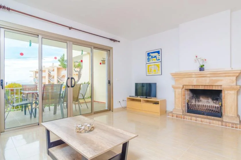 Una sala luminosa con comedor acristalado, televisor y chimenea.