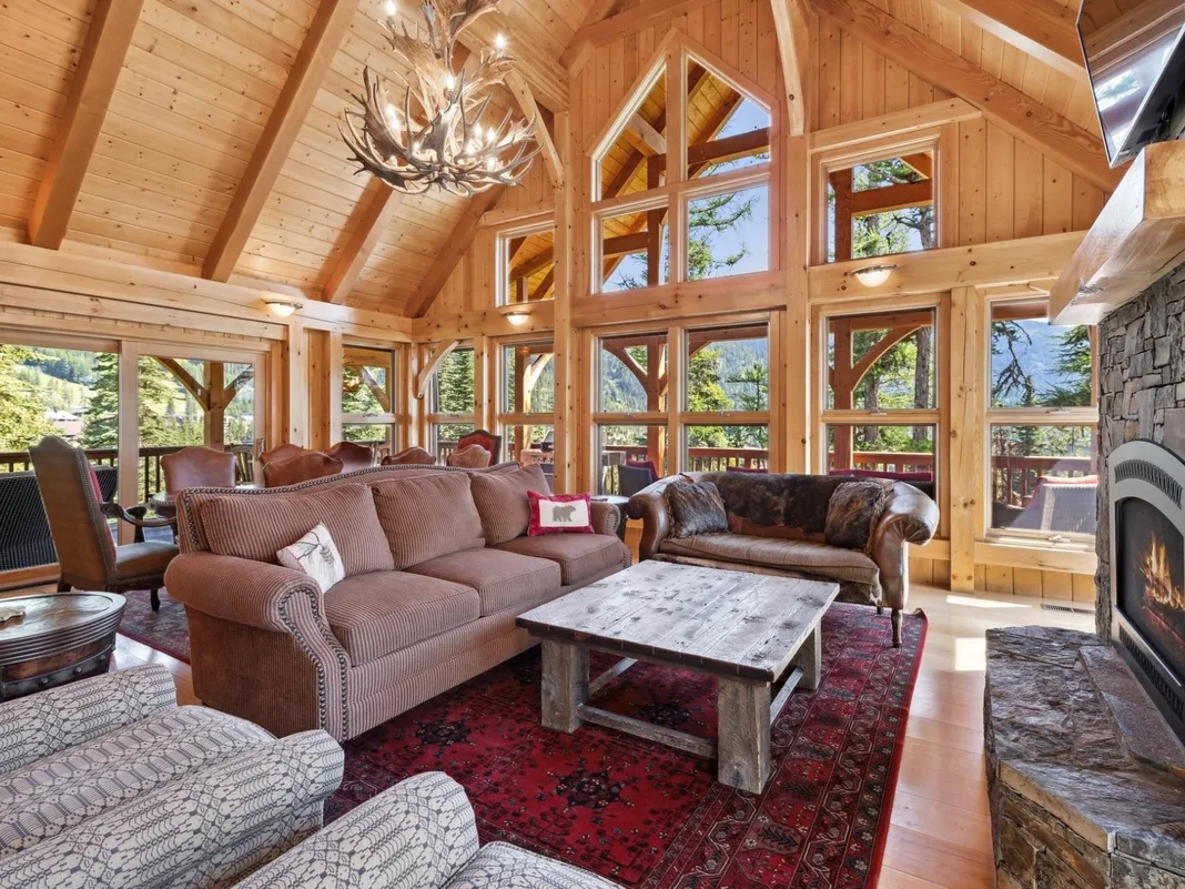 A wood-paneled living room with large windows and seating around a coffee table.