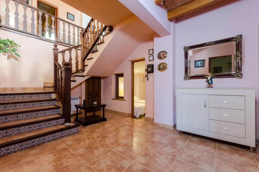 Un pasillo interior con suelo de baldosas y una escalera.