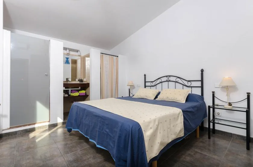 Un dormitorio con una cama tendida y lámparas a ambos lados.