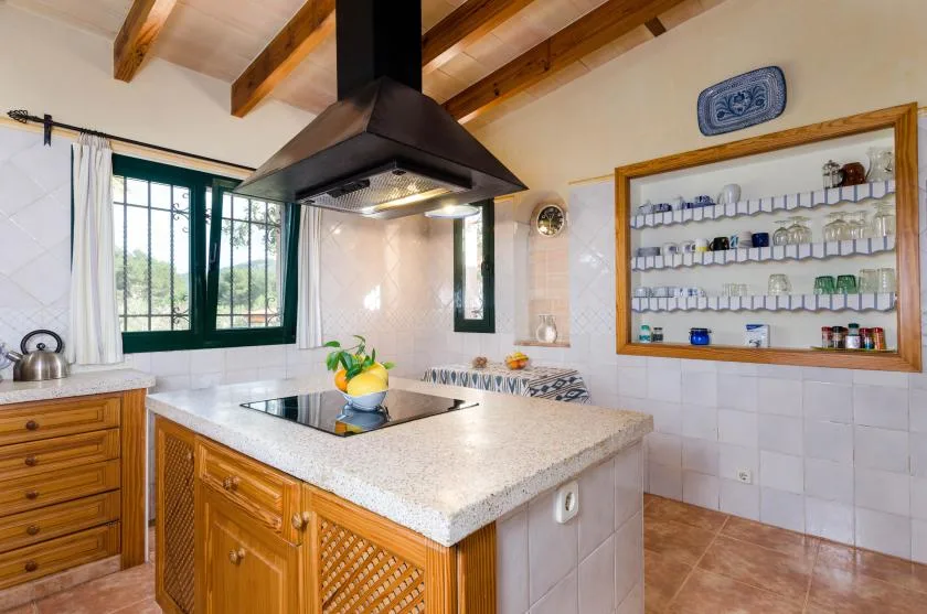 Una cocina luminosa con gabinetes de madera, una isla central y una campana extractora grande.