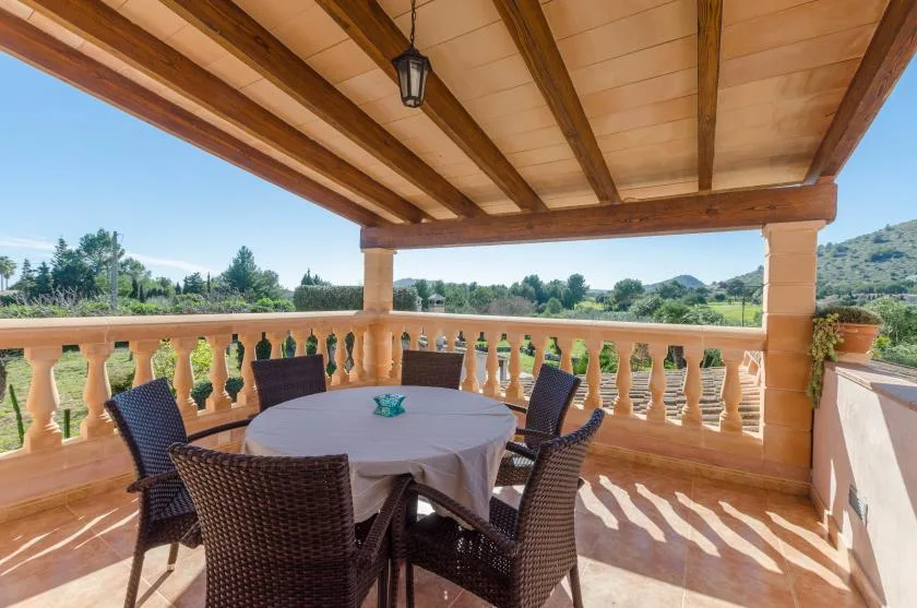 Una terraza exterior cubierta con una mesa redonda frente a un paisaje verde.