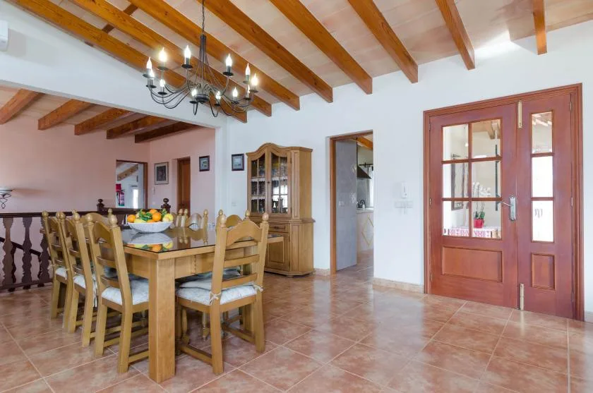 Un comedor con una mesa y sillas de madera bajo vigas expuestas.
