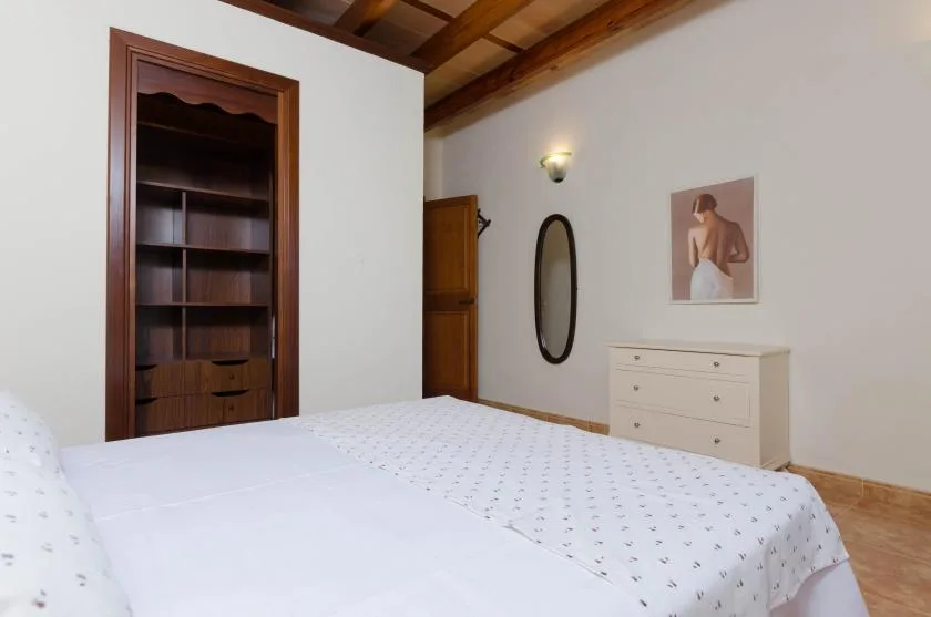 Un dormitorio con una cama, estanterías de madera y una cómoda blanca.