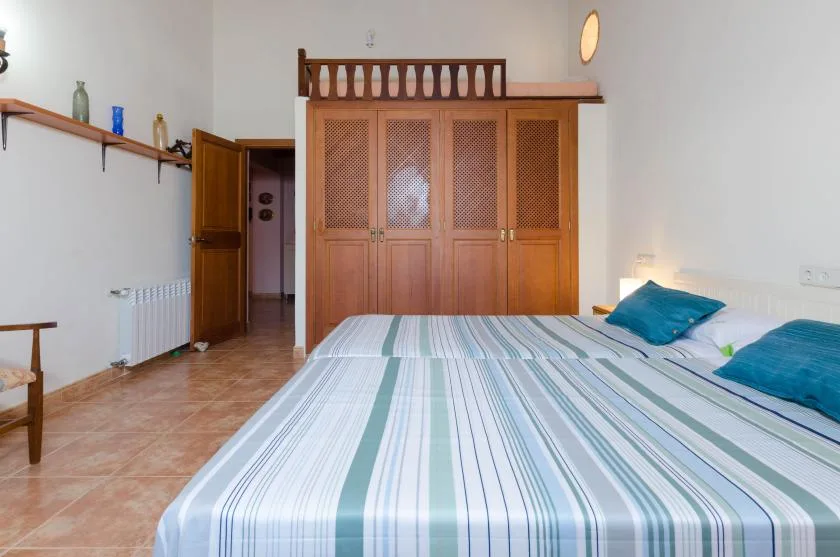 Un dormitorio con una colcha a rayas y un armario de madera.