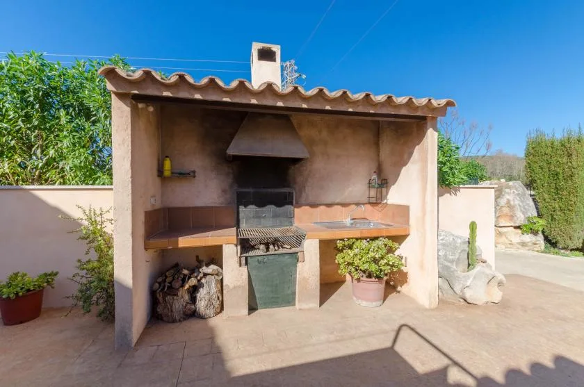 Una zona de barbacoa exterior de mampostería con techo de tejas y encimera.