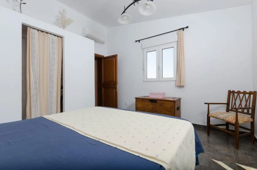 Un dormitorio con una cama, una ventana con cortinas y una silla de madera.