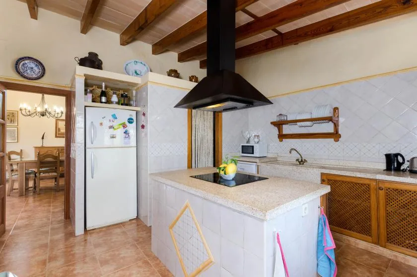 Una cocina con una isla central, refrigerador y vigas de madera en el techo.