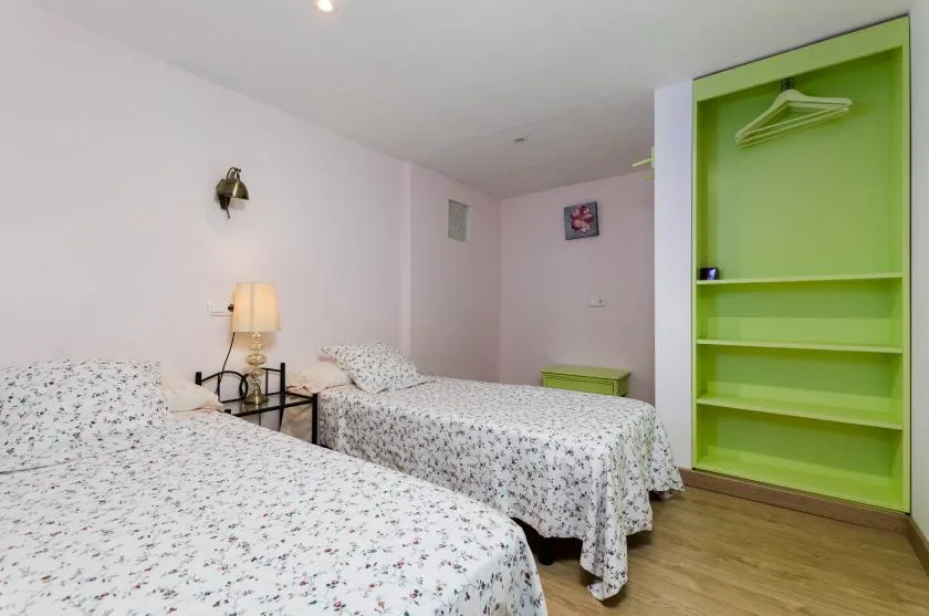Un dormitorio con dos camas, una mesita de noche y un armario abierto verde.