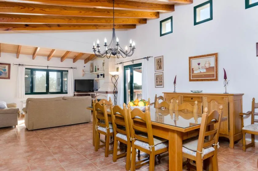 Comedor y sala de estar con una mesa de madera y asientos bajo vigas vistas.