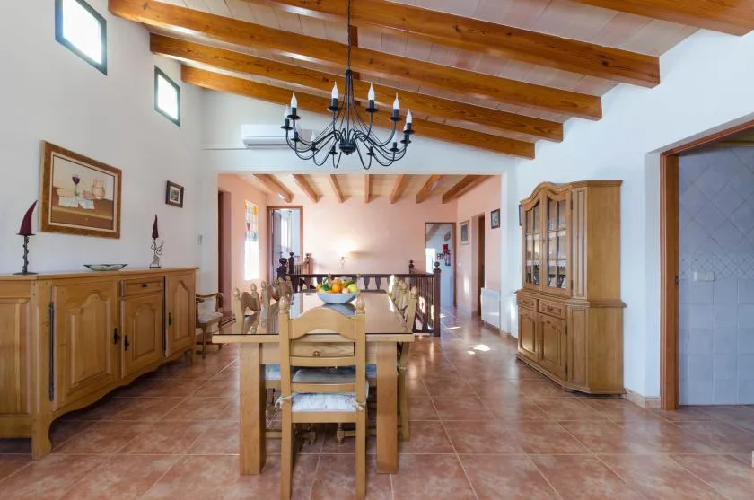 Un comedor con una mesa de madera bajo vigas vistas en el techo.