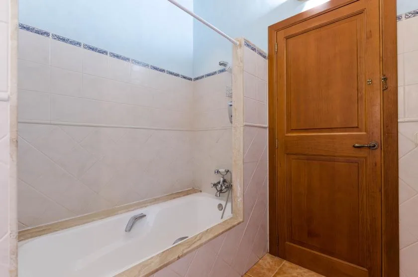 Un baño alicatado con una bañera junto a una puerta de madera.
