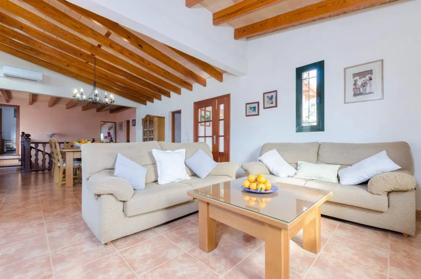 Una sala de estar con asientos claros y una mesa de centro de madera.