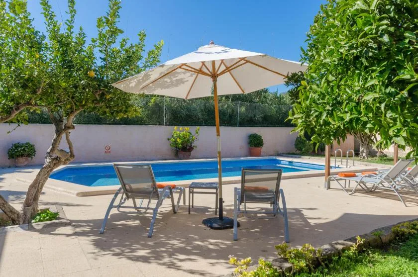 Una piscina al aire libre con asientos reclinables y una sombrilla grande.