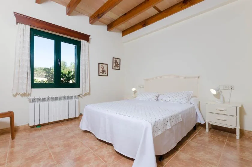 Un dormitorio con una cama doble, mesitas de noche y una ventana.