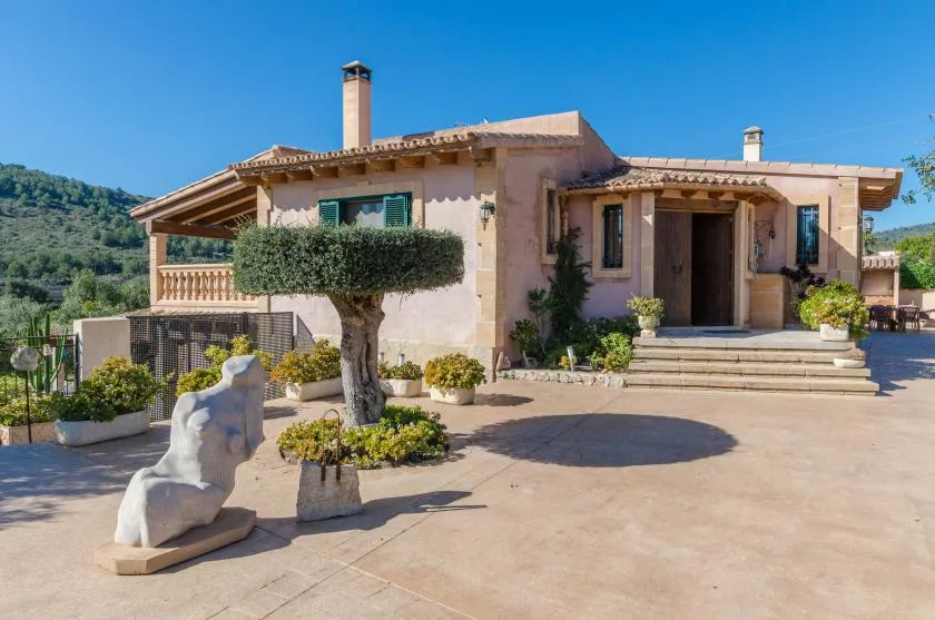 Una casa estucada con un amplio patio pavimentado y jardineras.